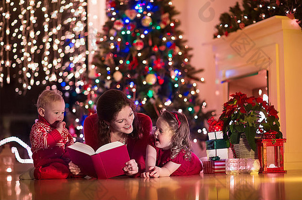 家庭圣诞节夏娃壁炉妈妈。孩子们开放圣诞节礼物孩子们礼物盒子