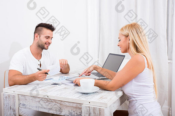 美丽的年轻的夫妇坐着表格讨论业务