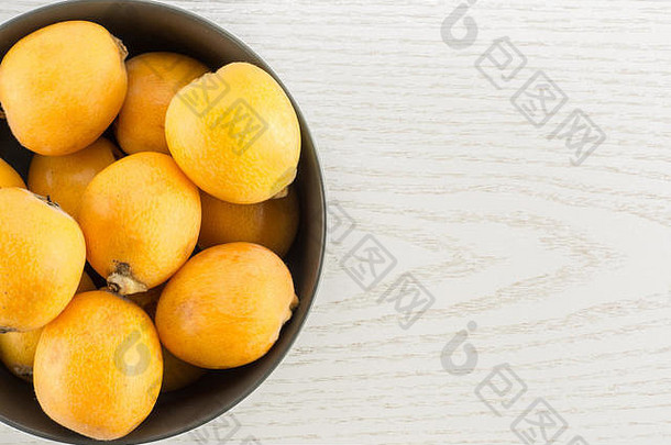 新鲜的橙色日本枇杷灰色陶瓷碗平铺孤立的灰色木背景
