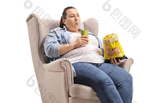 超重女人坐着扶手椅吃垃圾食物孤立的白色背景