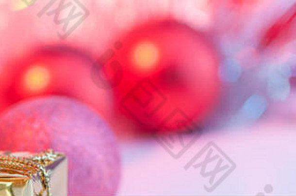 快乐圣诞节一年礼物黄金盒子红色的圣诞节球堆左角落里背景粉红色的