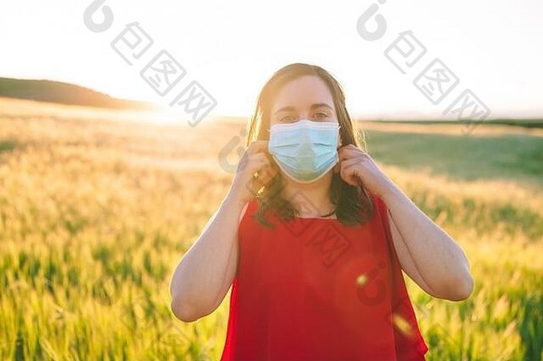 快乐快乐的年轻的女人删除医疗脸面具站草地在户外日落春天概念结束冠状病毒流感大流行高质量照片