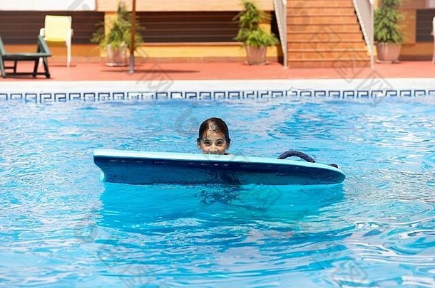 可爱的女孩玩bodyboard游泳池
