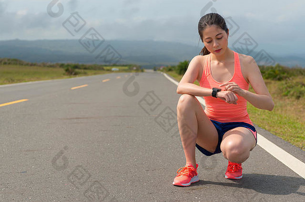 有吸引力的年轻的女人蹲沥青路锻炼心率智能手表准备好了培训个人耐力马拉松游戏
