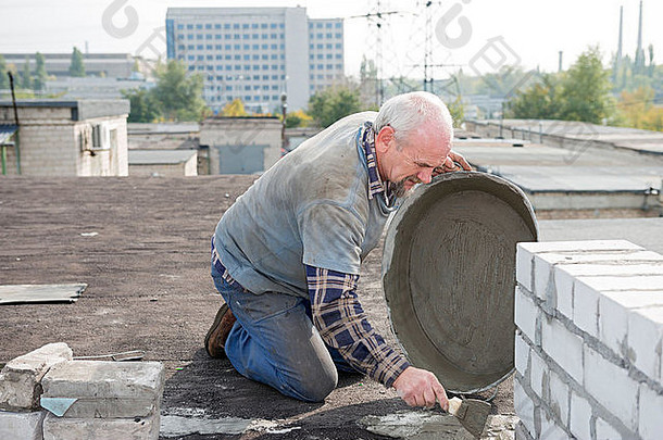 岁的首页盖屋顶的人准备砂浆盆地修复屋顶的水泥冗长的防水纸