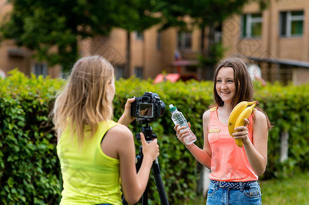 年轻的女孩夏天自然告诉适当的营养手瓶水香蕉记录视频博客博客用户记录视频教训互联网相机三脚架