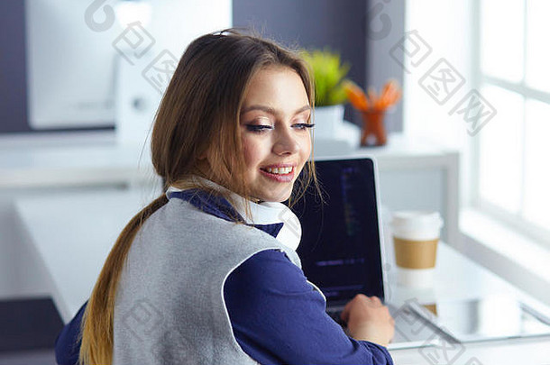 集中细心的女人耳机坐在桌子上移动PC屏幕使笔记学习外国语言互联网