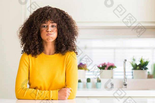 非洲美国女人穿黄色的毛衣厨房吸烟脸颊有趣的脸口膨胀的空气疯狂的表达式