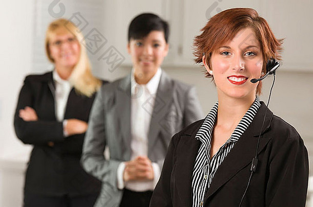 漂亮的红色的头发的女商人耳机的同事们办公室设置