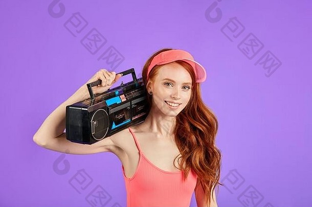 红发年轻的女人雀斑相机微笑持有立体声盒式磁带磁带球员肩膀穿粉红色的太阳帽有氧