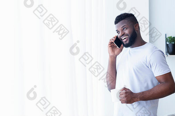 快乐的黑色的男人。会说话的移动电话窗口咖啡