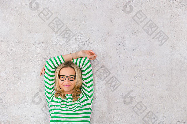 年轻的漂亮的金发女郎女人摆姿势前面混凝土墙穿绿色白色条纹毛衣