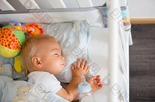 可爱的婴儿男孩睡觉瓶公式牛奶累了孩子婴儿床床上