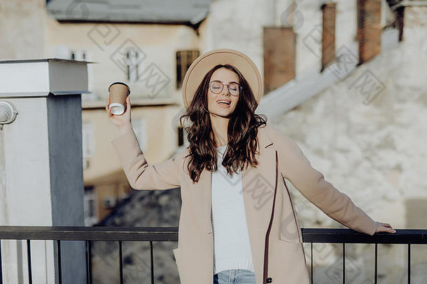 肖像高加索人女人穿外套眼镜喝外卖咖啡走城市街