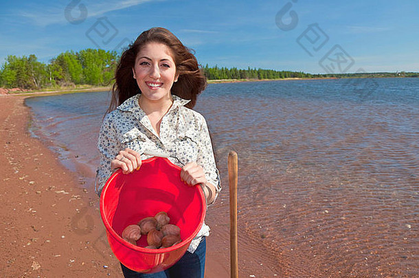 年轻的女人铲挖掘蛤