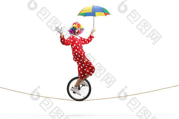 完整的长度配置文件拍摄小丑骑独轮脚踏车绳子持有伞孤立的白色背景