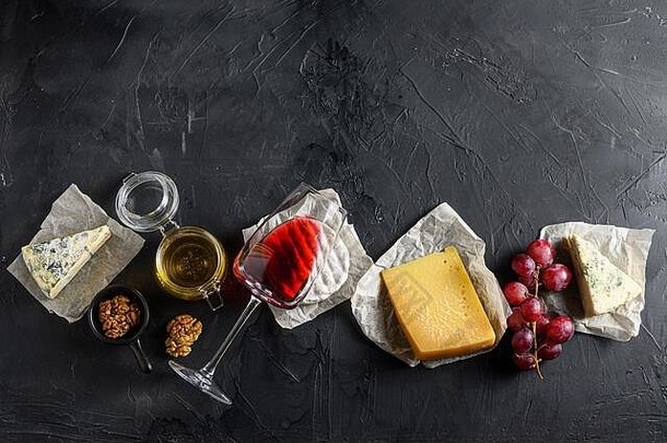 分类奶酪质antipasto玻璃红色的酒蜂蜜坚果香料黑色的背景石头板岩前视图免费的空间文本