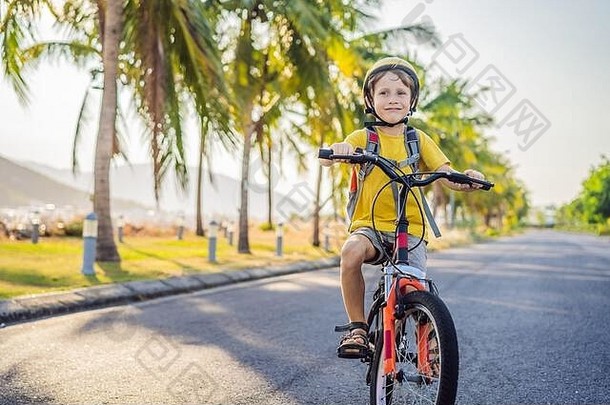 活跃的学校孩子男孩安全头盔骑自行车背包阳光明媚的一天快乐孩子骑自行车学校安全孩子们在户外