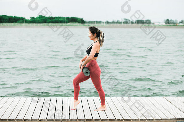 亚洲年轻的女孩瑜伽在户外码头湖她是穿黑色的前红色的紧身裤