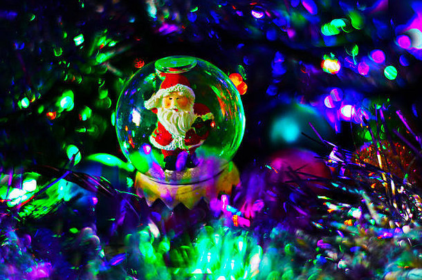 玻璃雪球圣诞老人老人内部节日模糊背景闪闪发光的灯俗丽的圣诞节一年神奇的背景临时