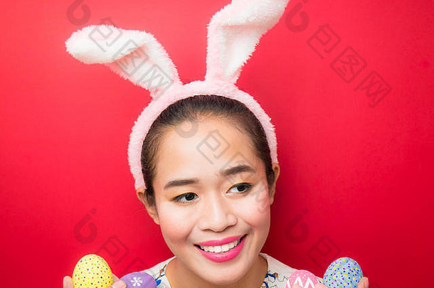 女人穿兔子耳朵头巾携带复活节鸡蛋复活节季节有吸引力的年轻的女人微笑明亮的红色的背景