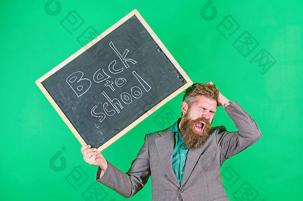 老师蓬乱的头发有压力的学校一年开始老师有胡子的男人。持有黑板上登记回来学校绿色背景工作教学有压力的占领