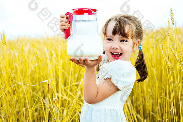 可爱的快乐女孩小麦场持有壶牛奶