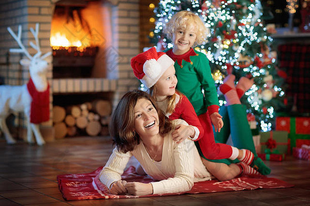 家庭孩子们圣诞节树壁炉妈妈。孩子们开放礼物火的地方男孩女孩妈妈开放礼物冬天假期
