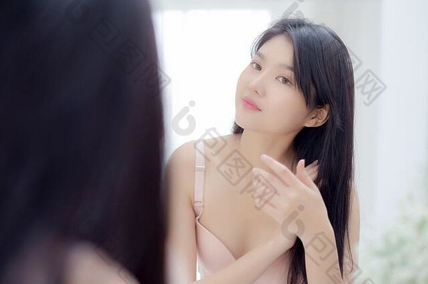 美丽的年轻的亚洲女人微笑镜子触摸头发房间化妆品卫生头发护理美亚洲女孩快乐发型三