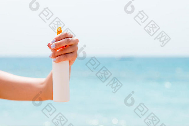 作物图像女人的手持有防晒霜喷雾海滩
