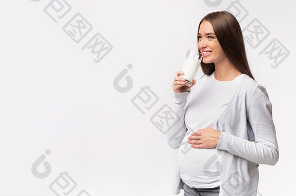 快乐怀孕了女孩喝牛奶灰色的工作室背景全景