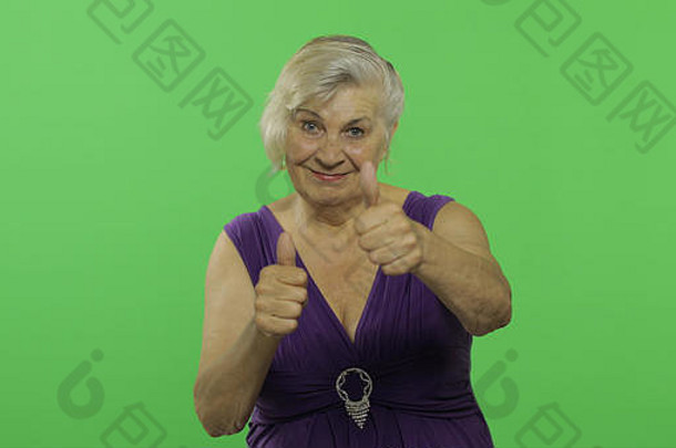 上了年纪的女人显示拇指微笑漂亮的祖母紫色的衣服的地方标志文本浓度关键绿色屏幕背景