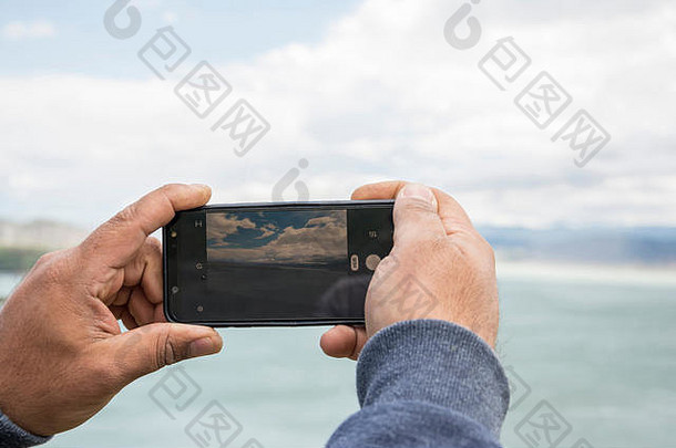 关闭智能手机相机屏幕拍摄美丽的景观男人。手持有移动采取图片