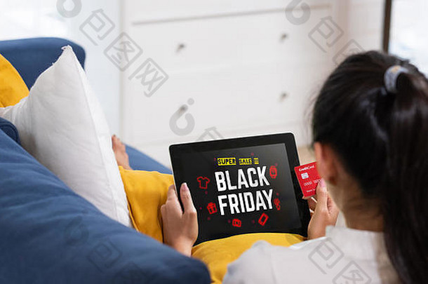 亚洲女人在线购物信贷卡黑色的周五出售平板电脑坐着沙发首页数字生活方式技术
