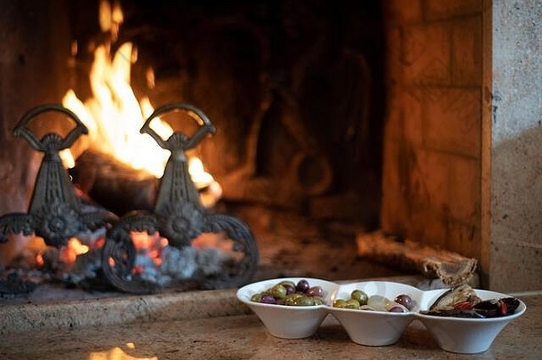 碗意大利橄榄与燃烧火砖壁炉冷冬天一天关闭