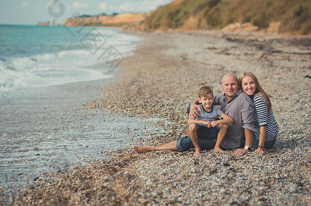 可爱的令人惊异的场景快乐家庭英俊的父亲美丽的夫人妈妈。可爱的儿子男孩摆姿势海一边海洋石头海滩