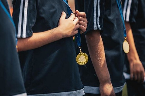 体育孩子们球员金奖牌站行庆祝活动奖牌挂年轻的体育运动球员脖子