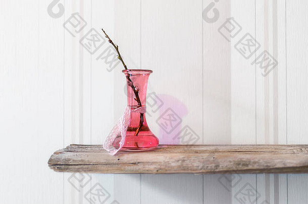 粉红色的玻璃瓶开花了分支站木前面明亮的壁纸