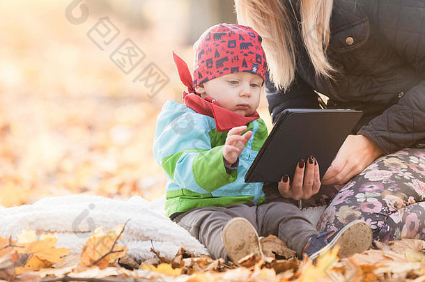 妈妈。婴儿男孩坐着毯子公园数字平板电脑年轻的妈妈教孩子平板电脑触屏小孩子