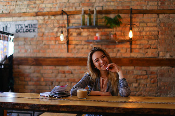微笑女坐着表格杯卡布奇诺咖啡笔记本舒适的咖啡馆