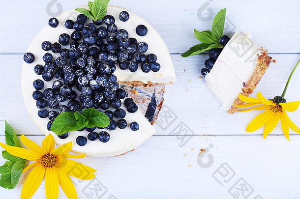 甜蜜的奶油蓝莓芝士蛋糕新鲜的蓝莓薄荷叶子黄色的花减少一块白色木背景复制空间