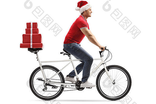 完整的长度拍摄年轻的男人。圣诞节他骑串联自行车携带礼物回来座位孤立的白色背景