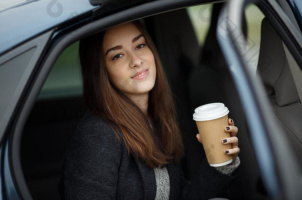肖像美丽的年轻的女人坐着车咖啡