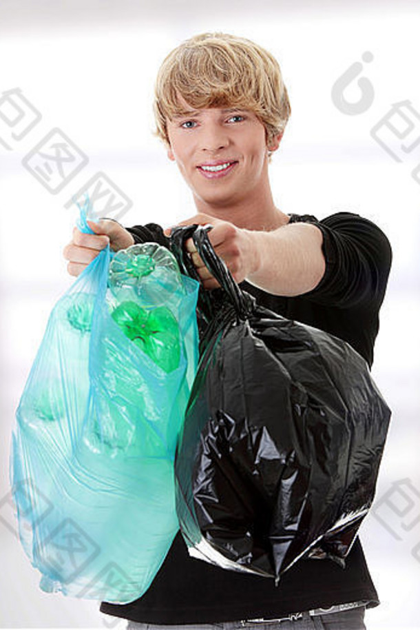年轻的男人。携带塑料垃圾袋完整的空可回收的家庭材料
