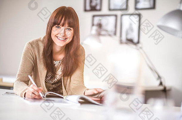 肖像微笑年轻的女商人工作桌子上办公室