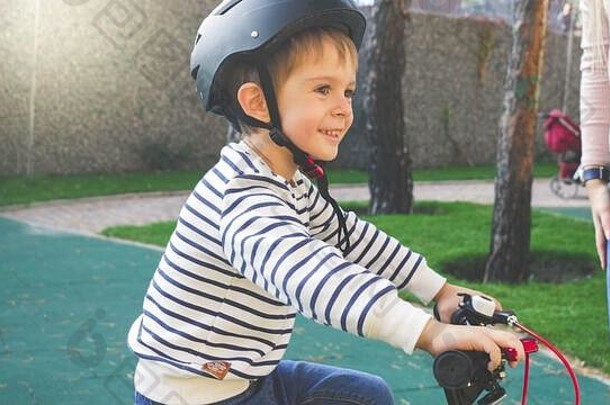 健美的肖像快乐的微笑男孩黑色的保护头盔骑自行车