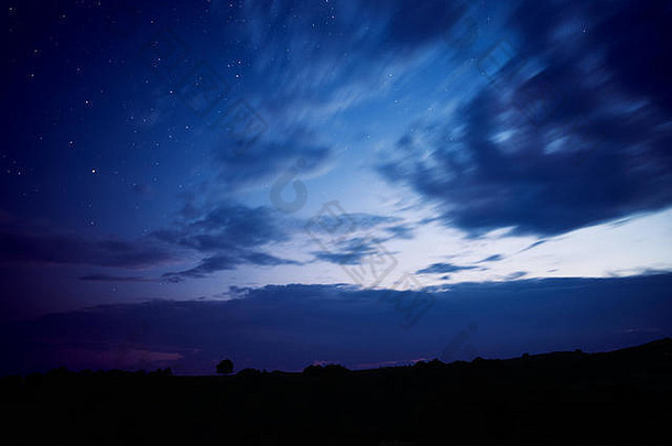 晚上景观蓝色的小时轮廓孤独的树山布满星星的天空完整的云长曝光