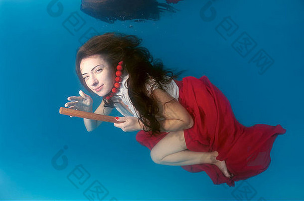 年轻的女人大头发摆姿势池水下