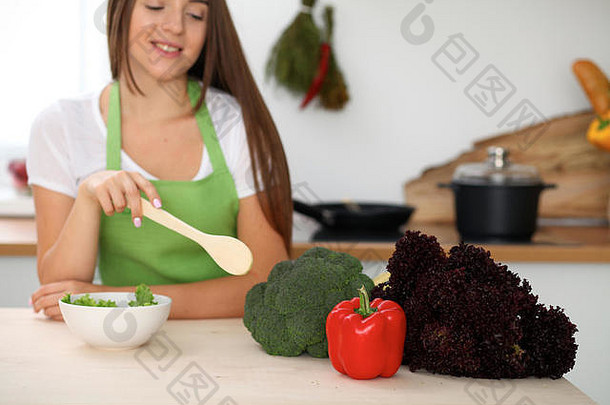 年轻的女人烹饪健康的餐蔬菜厨房关闭家庭主妇木勺子指出沙拉布罗利素食者概念