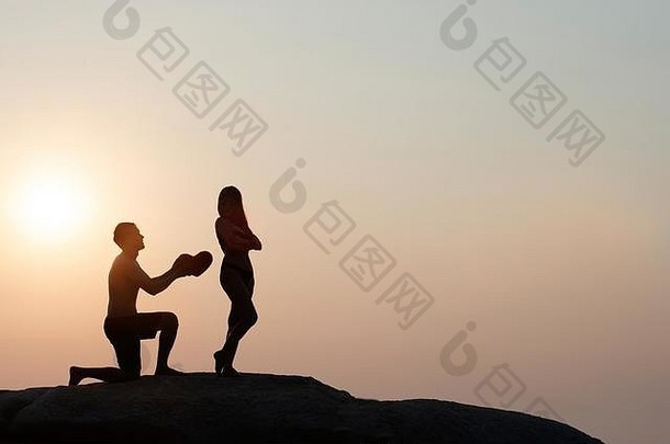 可爱的年轻的成人夫妇站岩石热带海日落